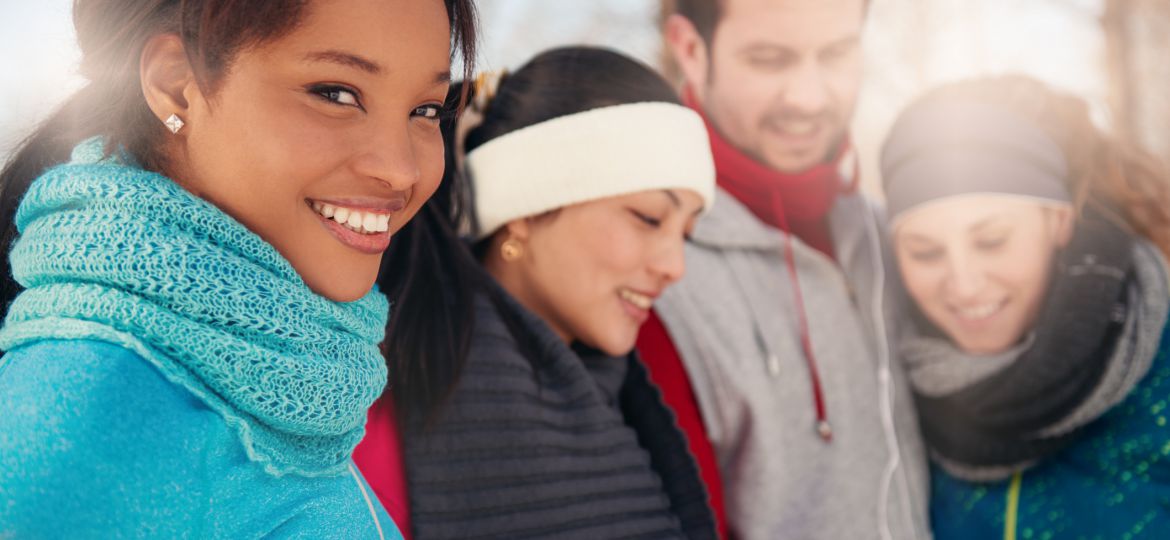 Group of friends listening to music in the snow in winter